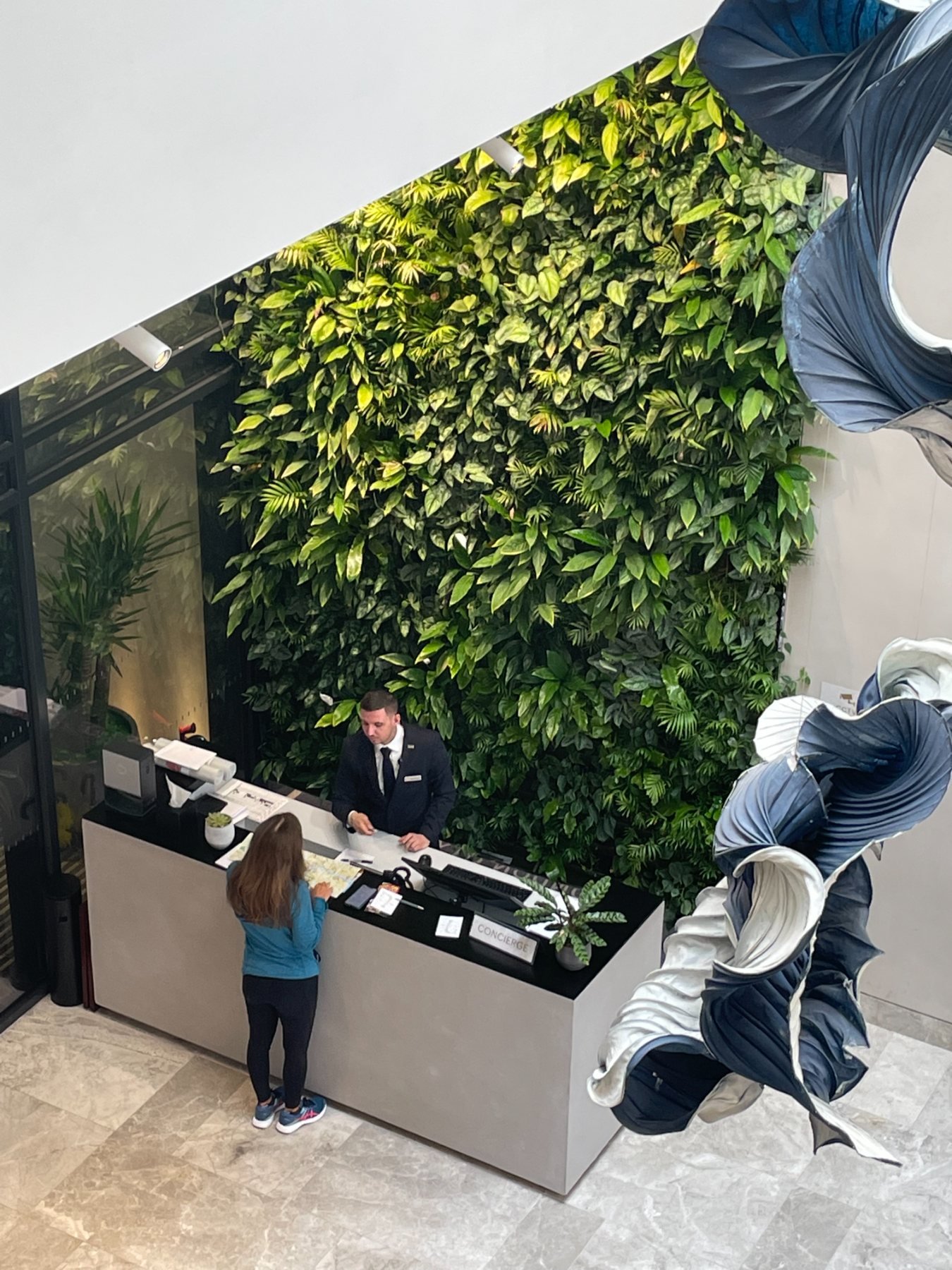 Interior living wall behind a retail reception desk with staff and customers in a marble lobby